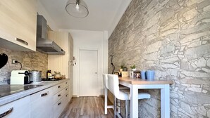 A compact kitchen with a stone wall, a white countertop, and a bar stool. - Le Conchiglie Di Grace - Apartment With Balcony (Alassio)