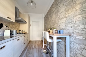 A compact kitchen with a stone wall, a white countertop, and a bar stool. - Le Conchiglie Di Grace - Apartment With Balcony (Alassio)