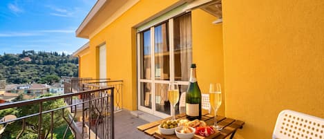 En balkon med et bord dækket til et måltid, en vinflaske og glas.