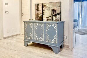 Une pièce avec un meuble bleu clair orné de motifs blancs travaillés, une assiette posée sur le dessus et un tableau encadré au-dessus.