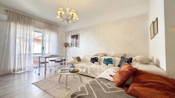Un salon moderne comprenant un canapé, une table basse et un coin repas avec des chaises.
