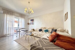 En moderne stue med sofa, sofabord og et spiseområde med stole.