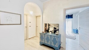 A hallway with a blue cabinet, a framed artwork, and a door leading to another room. - Le Conchiglie Di Grace - Apartment With Balcony (Alassio)