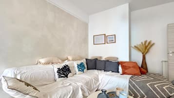 Un salon moderne avec un grand lit, une table basse ornée de bougies et un mur sur lequel sont accrochées deux images encadrées.