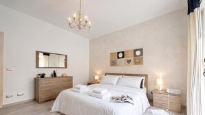 A modern bedroom with a large bed, bedside lamps, a wooden dresser, and a mirror. - Le Conchiglie Di Grace - Apartment With Balcony (Alassio)