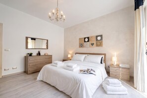 A modern bedroom with a large bed, bedside lamps, a wooden dresser, and a mirror. - Le Conchiglie Di Grace - Apartment With Balcony (Alassio)