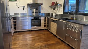 Une cuisine moderne dotée d’appareils électroménagers en acier inoxydable, d’armoires en bois et d’un plancher en bois.