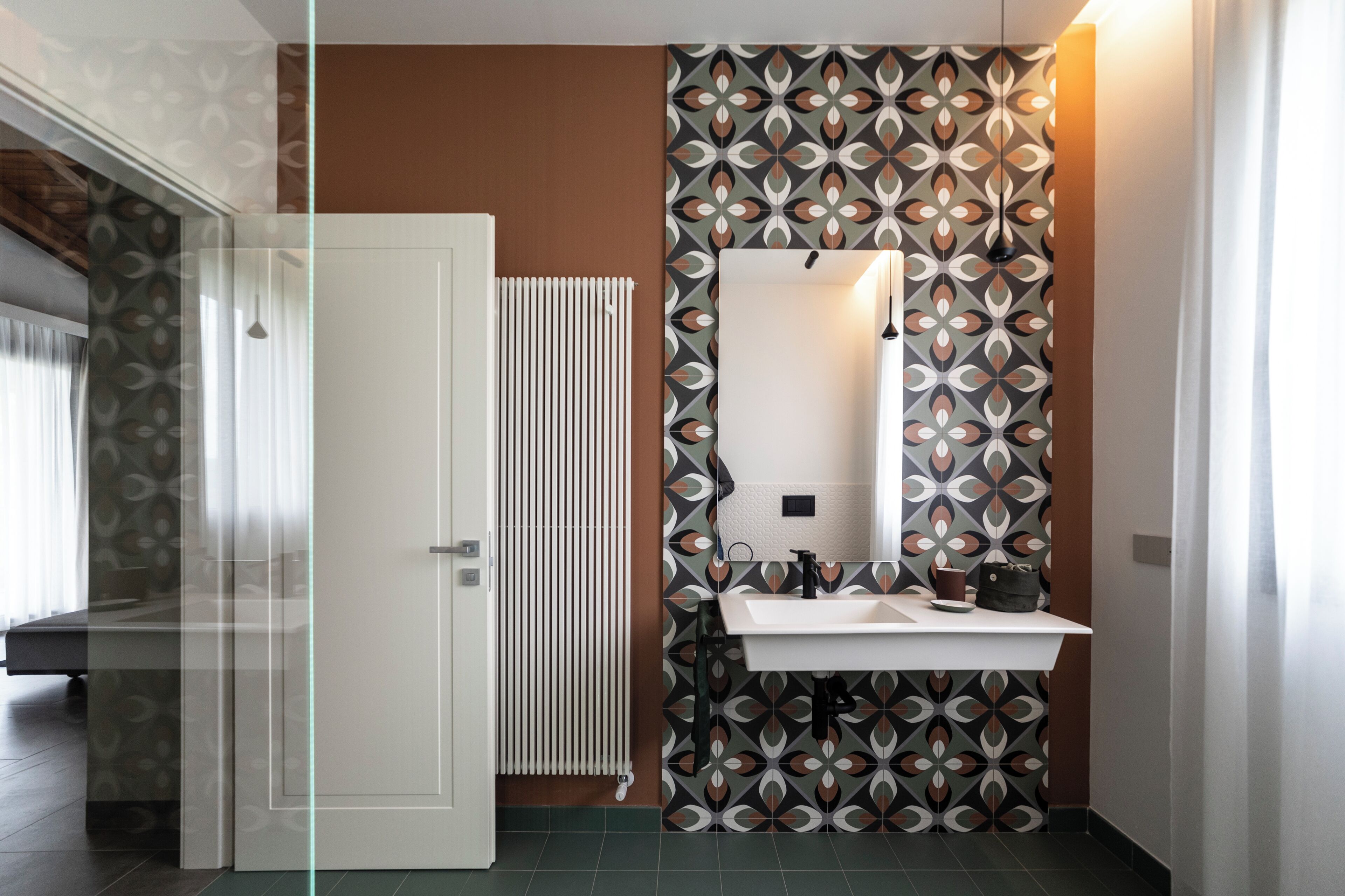 A modern bathroom with a patterned wall, a white sink, and a mirror.