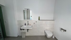 Uma casa de banho moderna com uma pia branca, espelho e sanita.
