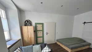 Um quarto pequeno e bem iluminado, com sofá, armário, cama e janela.