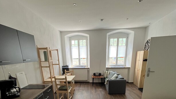 Quarto compacto com cozinha compacta, área de refeições, sofá e cama.