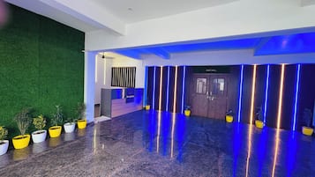Un vestíbulo moderno con mostrador de recepción, pared verde y un letrero que dice 'Party Hall'.