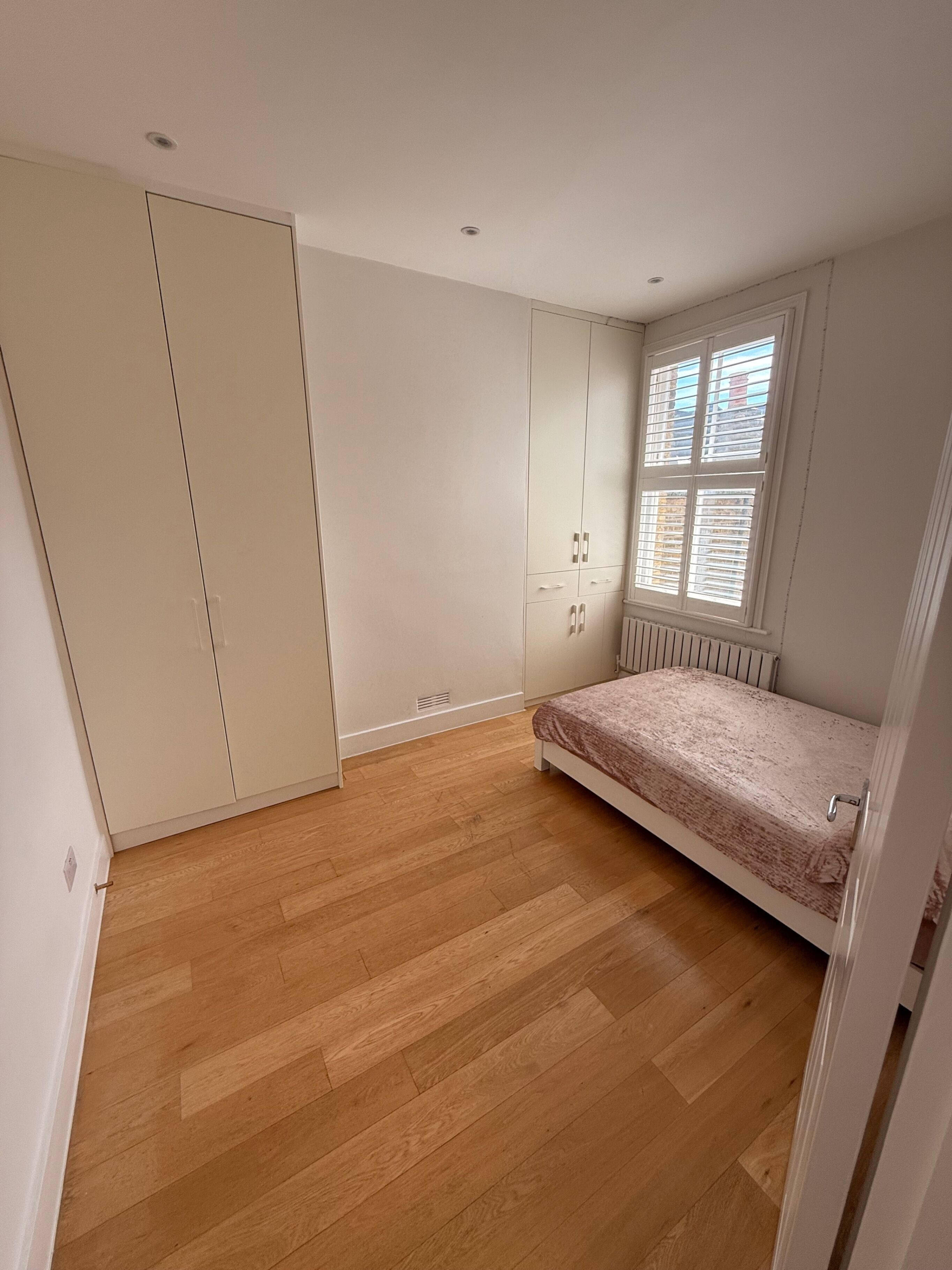 A bedroom with a bed, wardrobe, and window.