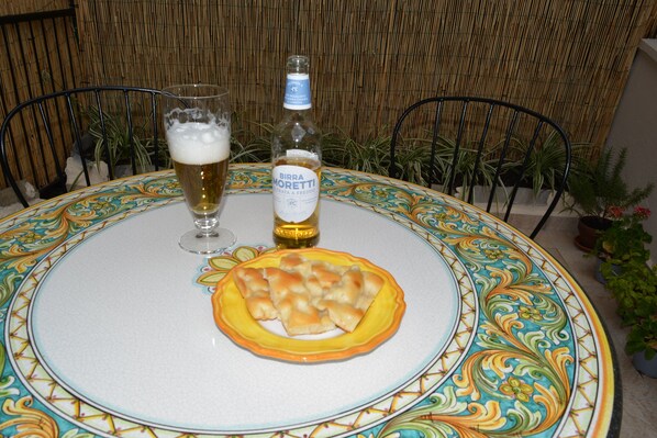 Una mesa con mantel colorido, una botella de cerveza Birra Moretti, una copa de cerveza y un plato de pizza.