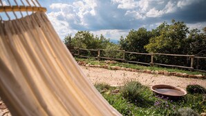 Un hamac dans un jardin, avec une clôture en bois, un mur de pierre et un bassin d’eau.