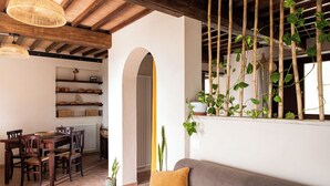 Un salon chaleureux avec un canapé, une table à manger en bois, des chaises et un mur végétal.