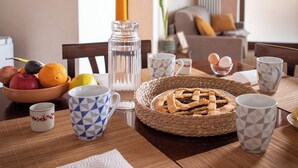 Une table à manger avec des fruits, une tarte et différentes tasses.