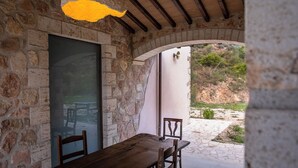 An outdoor dining area with stone walls, a wooden table, and chairs.