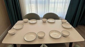 Ett matbord dukat för åtta personer, med åtta skålar och tallrikar, omgivet av fyra stolar.
