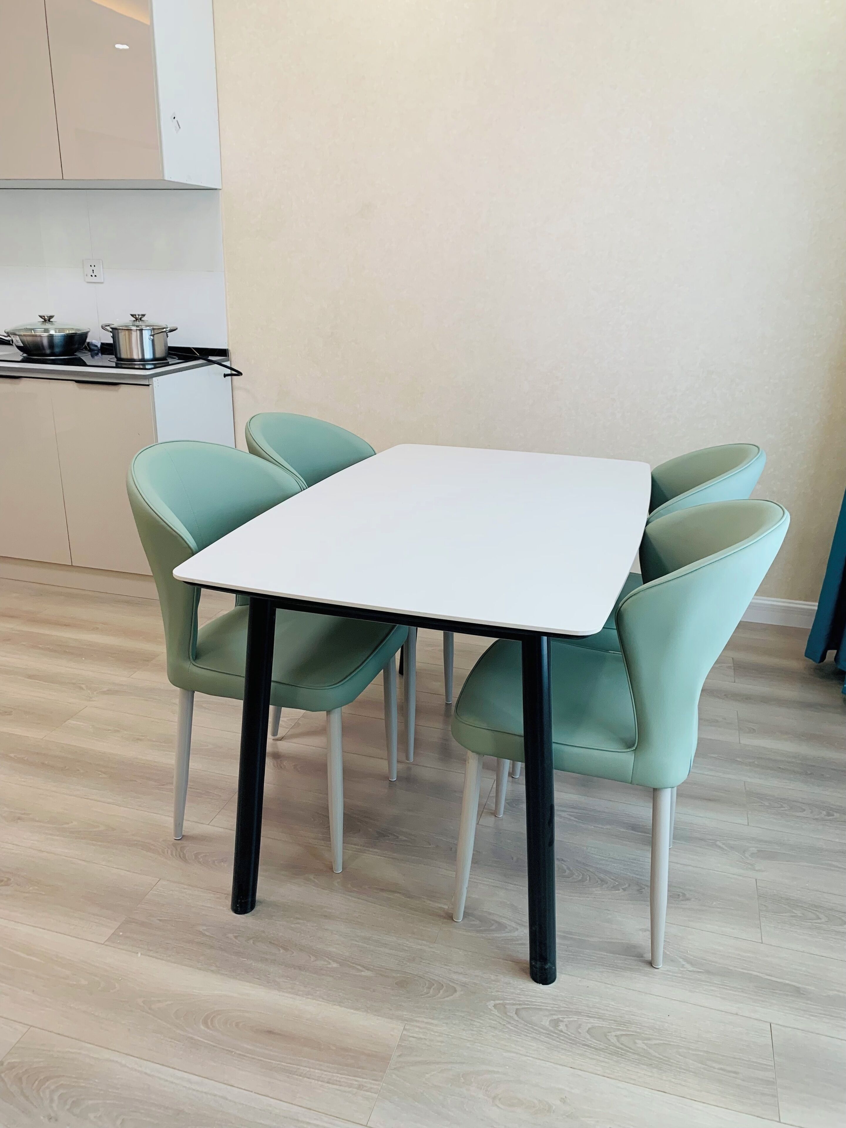Un comedor moderno con una mesa blanca y cuatro sillas verdes.