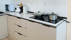 Une cuisine moderne avec des meubles blancs, un four à micro-ondes, une machine à café et une cuisinière.