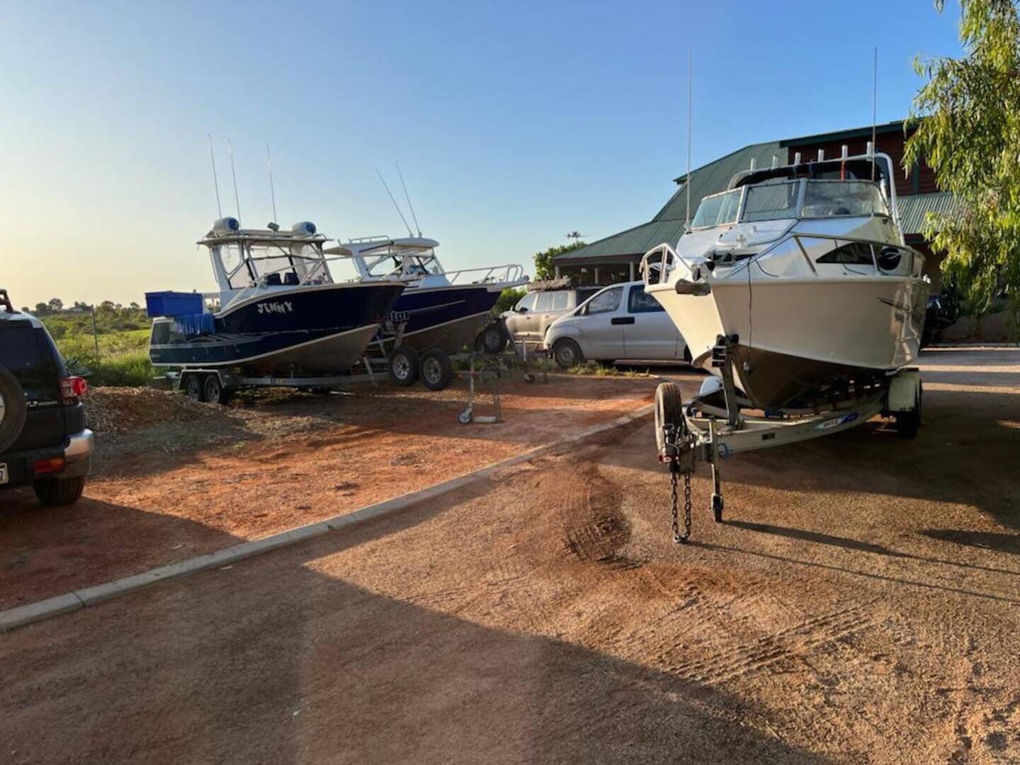 A boat trailer with a boat on it, parked on a dirt road.