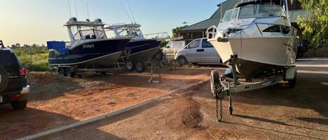 A boat trailer with a boat on it, parked on a dirt road.