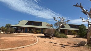 Un bâtiment à deux étages doté d’un toit végétalisé, un véhicule garé et un bateau dans l’allée.