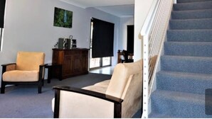 Un vaste salon doté d’un escalier, d’une cheminée et d’une grande fenêtre.
