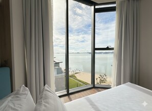 Une chambre d’hôtel dotée d’une grande fenêtre donnant sur la plage et l’océan.