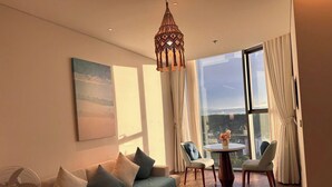 A modern living room with a sofa, a coffee table, and a view of the city through large windows. - Alacarte Ha Long - Ha Apartment (Bai Chay)