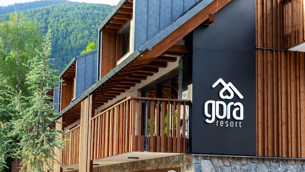 Ein modernes Gebäude mit einem Holzbalkon und einem Schild für 'Gora Resort'.