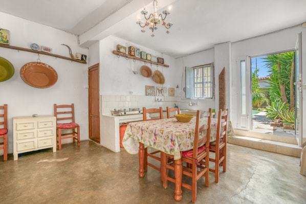 Une cuisine avec une table à manger, des chaises, un lustre et une vue sur l’extérieur.