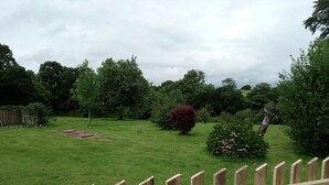 Un espace extérieur verdoyant, avec une clôture en bois, des arbres et un arbuste.