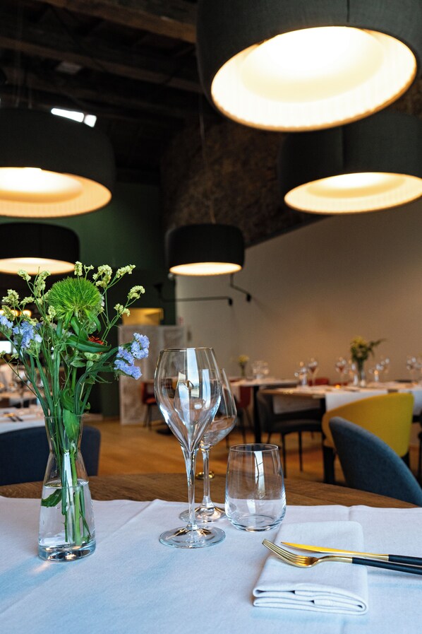 A dining table set with a vase of flowers, wine glasses, and cutlery.