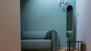 A staircase leading to a room with a light blue wall, a sofa, a small table, and a mirror. - Locanda Moderna Carlambroeus (Montevecchia)