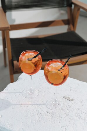 Dos vasos de una bebida con una rodaja de fruta sobre una superficie blanca.