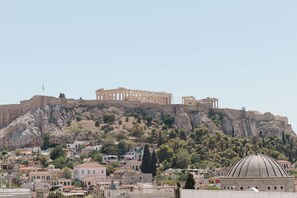 Un sitio histórico con ruinas antiguas en una colina, rodeado de edificios residenciales.