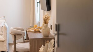 Una sala de estar moderna con una mesa de comedor de madera, un sofá cómodo, un televisor montado en la pared y un florero con plantas secas.