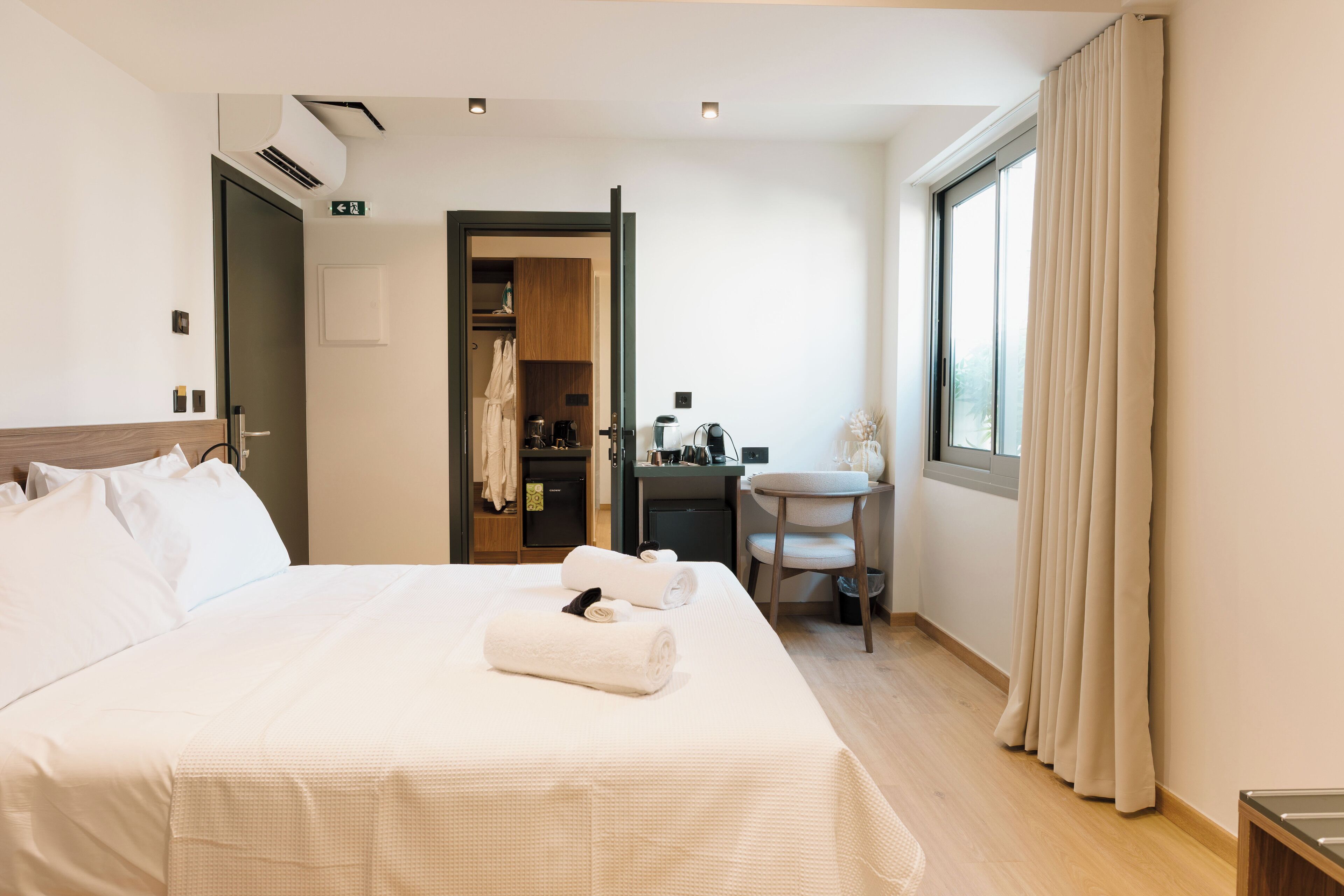 A hotel room with a large bed, a desk, a chair, and a window with curtains.