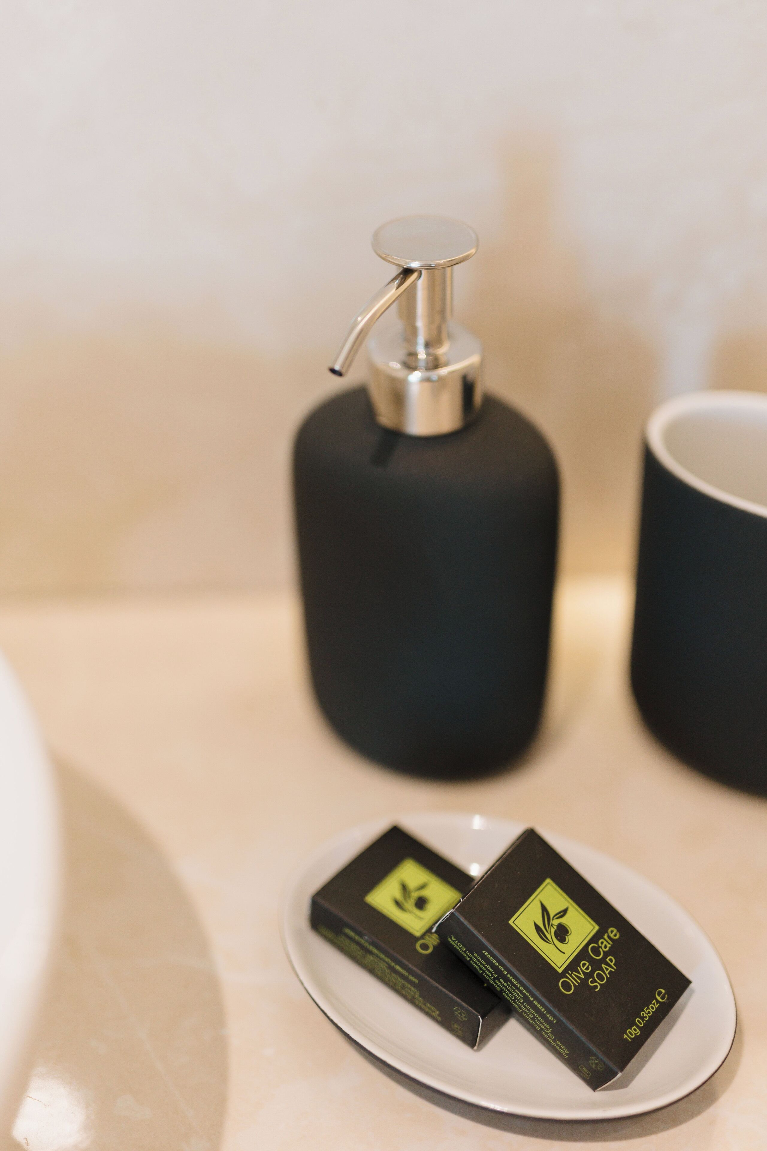 A bathroom sink with a black soap dispenser and a plate with two bars of soap.