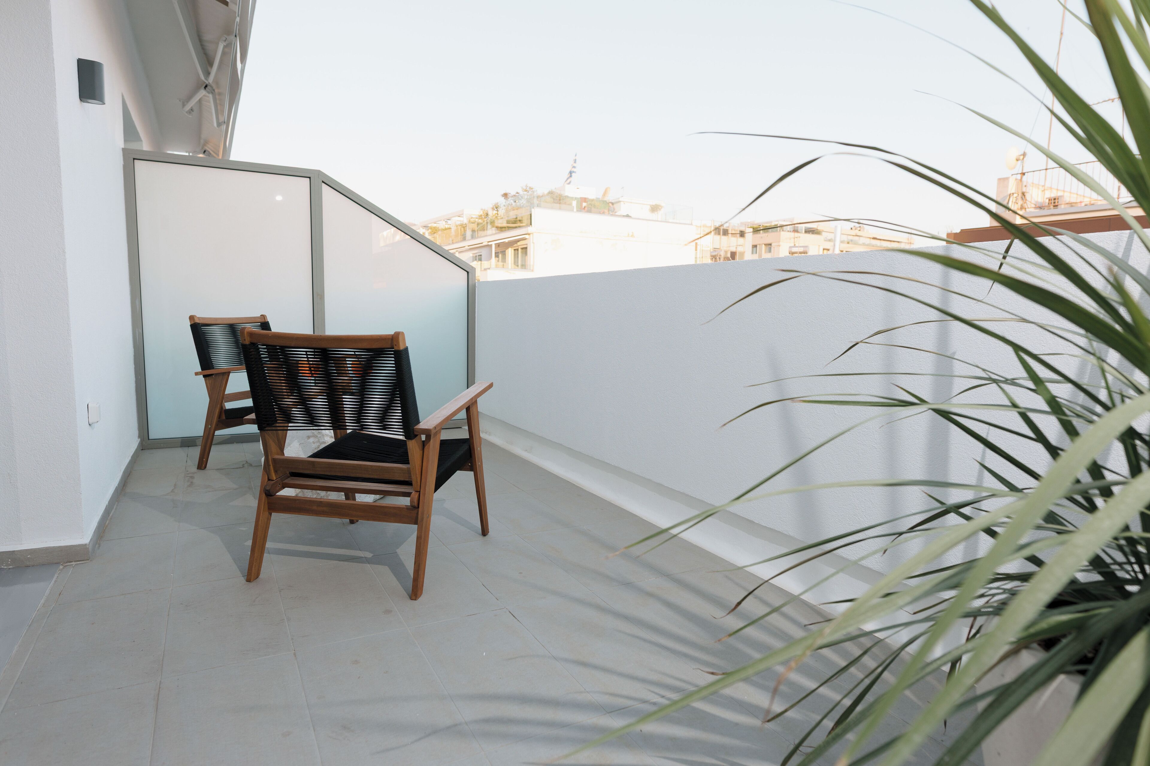 A balcony with two wooden chairs and a potted plant.