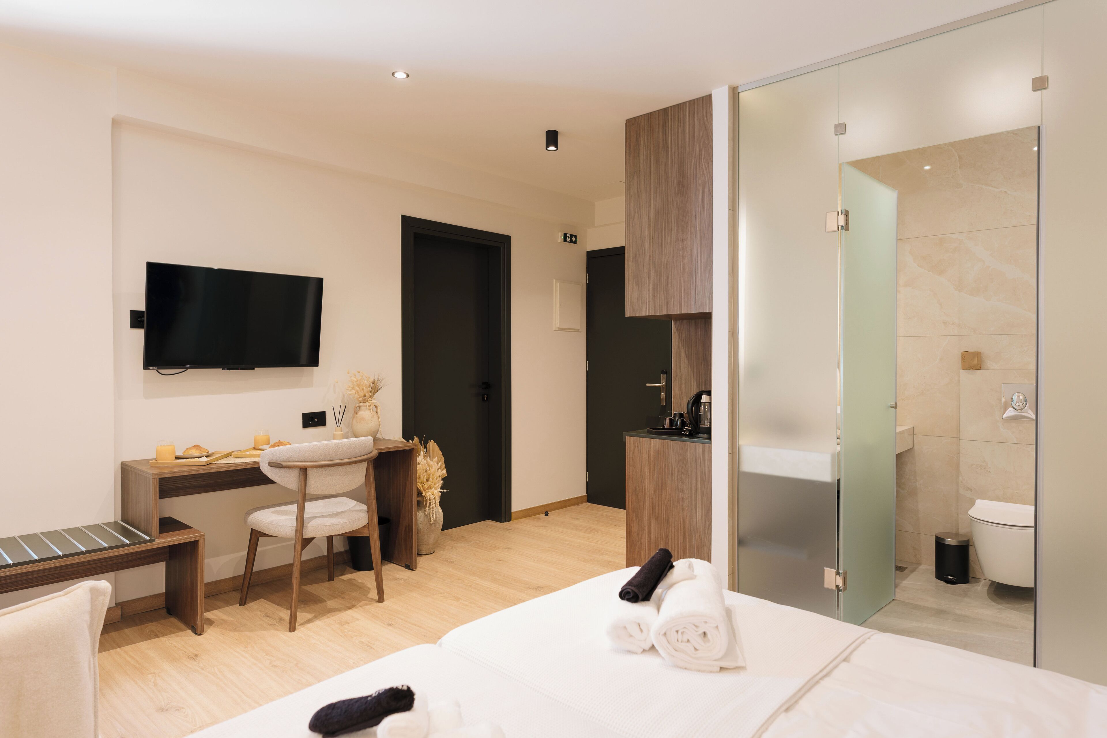 A modern hotel room with a bed, a desk, a TV, a bathroom, and a shower.
