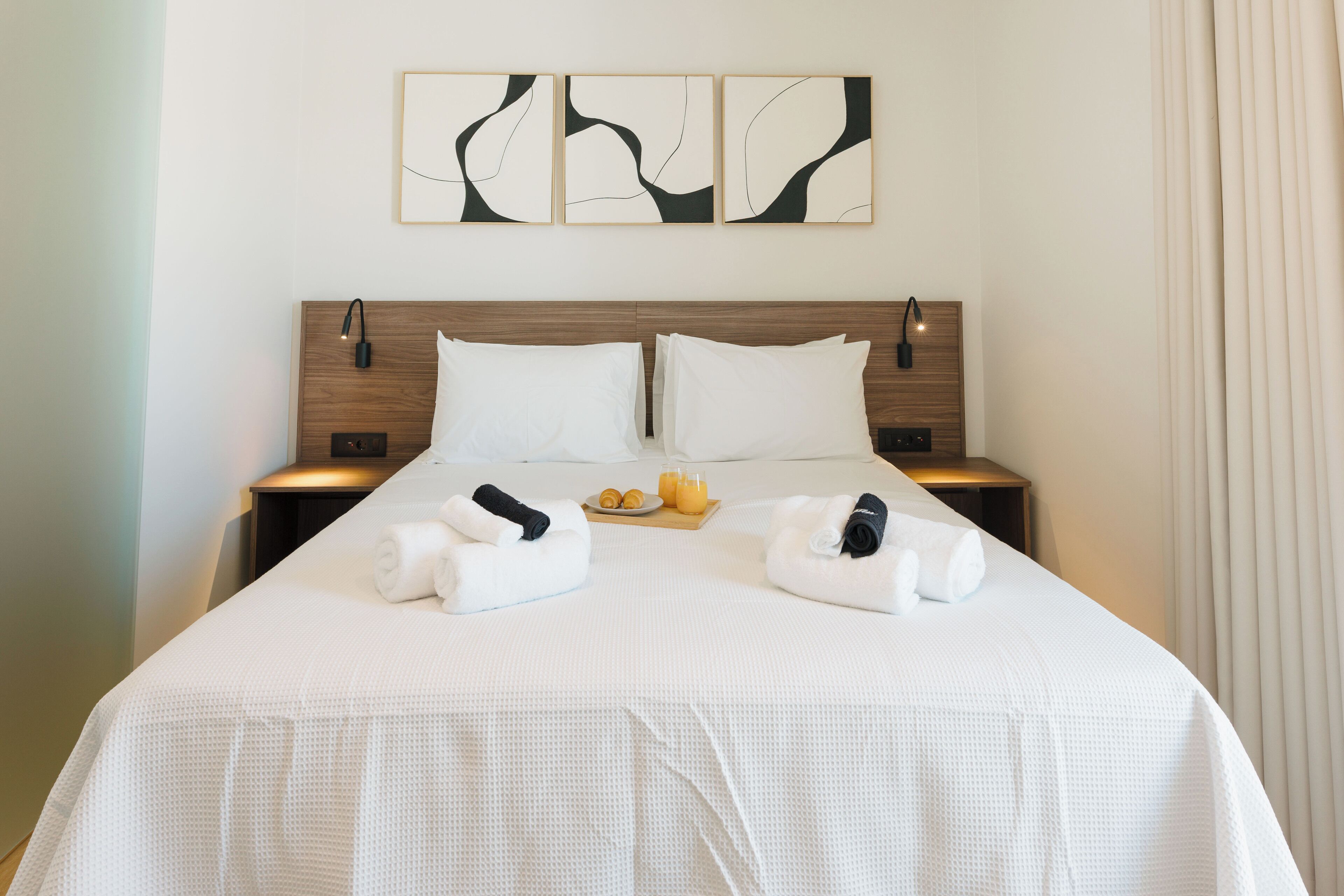 A hotel room with a large bed, two bedside tables, and a wall-mounted artwork above the bed.