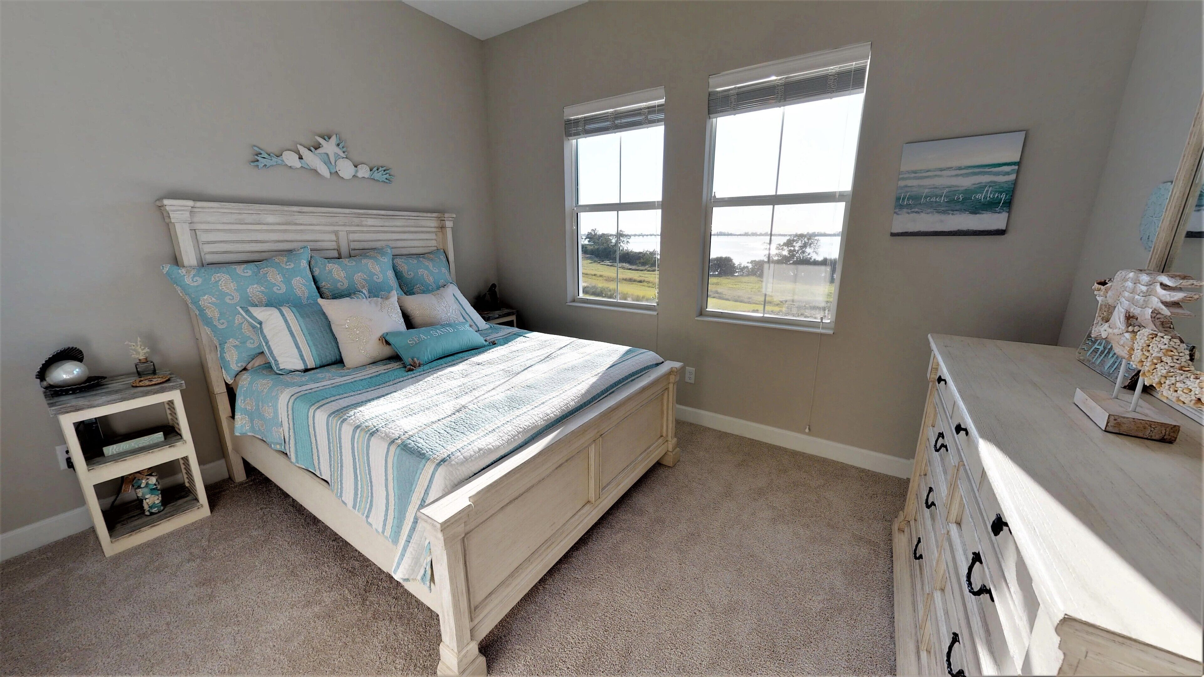 A bedroom with a bed, nightstands, a dresser, and a window with a view.