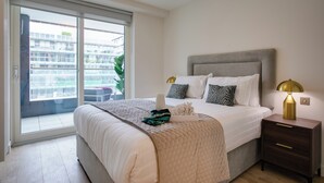 A bedroom with a large bed, a nightstand with a lamp, and a sliding glass door leading to an outdoor area. - The Benson Building (Dublin)