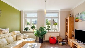 A living room with a sofa, a coffee table, a red bean bag, a TV, and a bookshelf. - Apartment Theo in the 'Alte Schule' Holiday Home with Mountain View, Shared Terrace & Wi-Fi (Ferna)