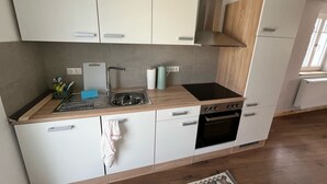 Cocina moderna con armarios blancos, pileta de acero inoxidable, estufa negra y horno integrado.