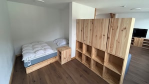 Un dormitorio con una cama de madera, una mesita de noche de madera y estanterías empotradas de madera.