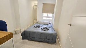Una habitación pequeña con cama, escritorio y ventana.